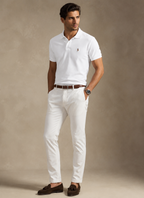 Man wearing a white polo shirt and white pants with a brown belt against a beige background