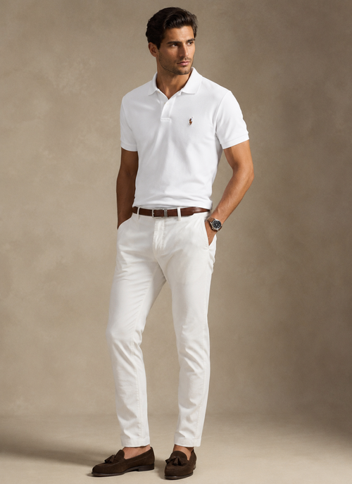 Man wearing a white polo shirt and white pants with a brown belt against a beige background